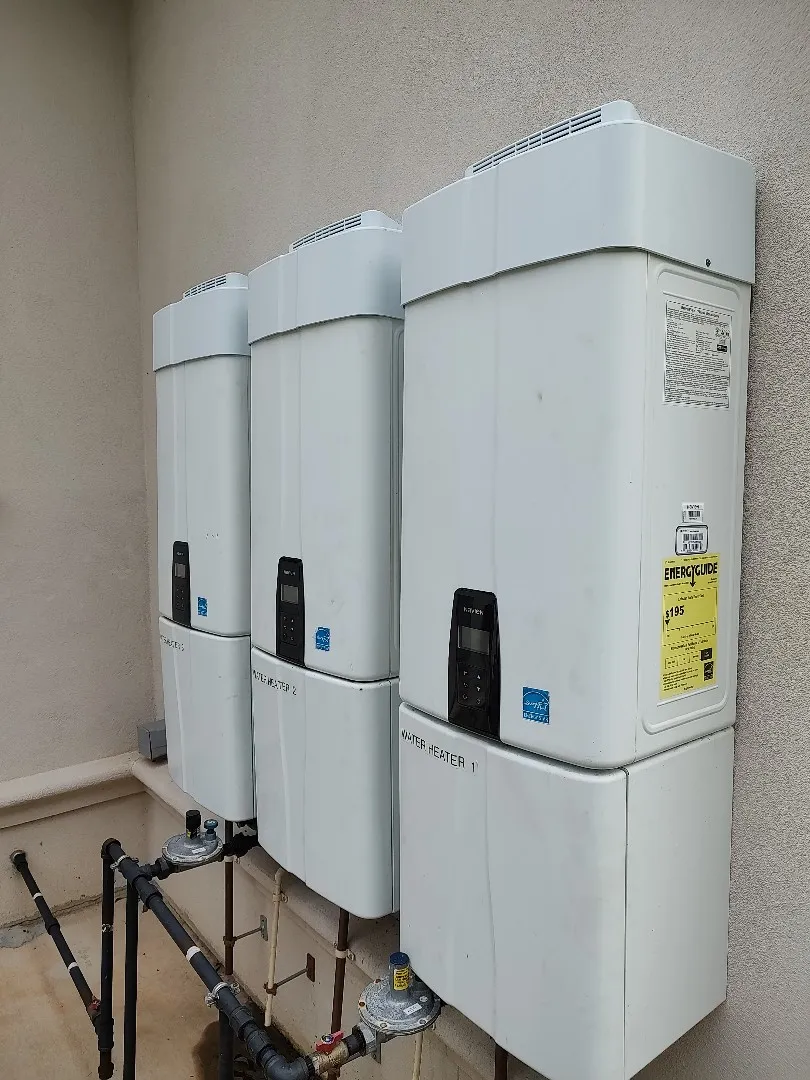 Three energy-efficient tankless water heaters installed outdoors, demonstrating professional plumbing installation for residential use.