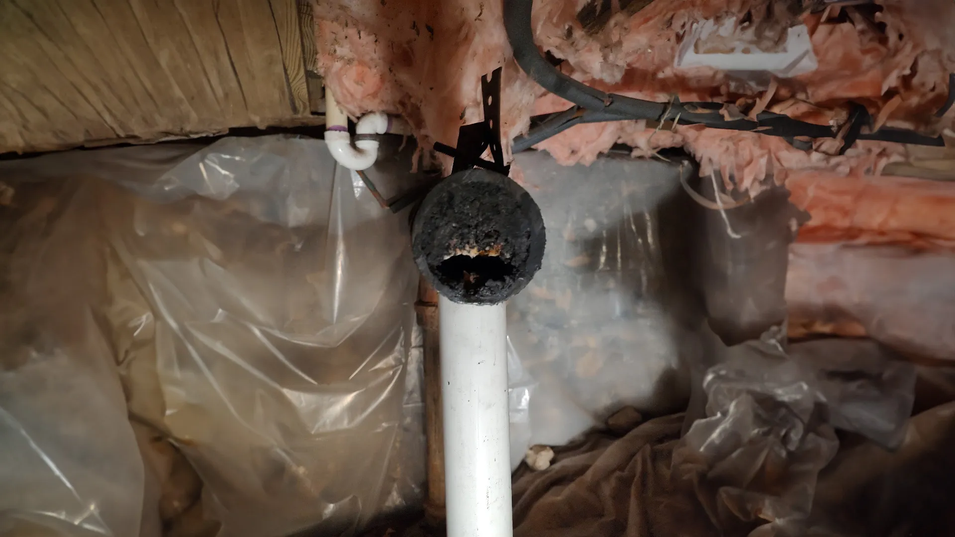 Damaged and corroded pipe in a crawl space, showing need for professional plumbing repair services.